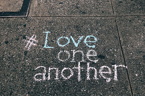 Pavement with chalk writing "Love one another"