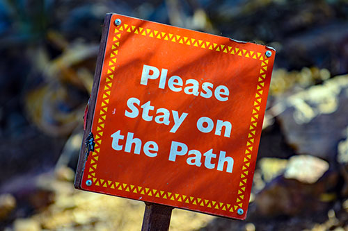 text on red paper "please stay on the path"